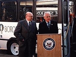 Congressman Pascrell with Mayor Steve Plate in front of a new white shuttle bus.  The Congressman stands behind a podium adorned with a house of representatives seal
