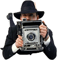 Image of a man on his stomach taking a picture with an old camera
