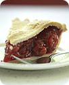 A slice of raspberry pie on a small plate with a fork beside it.