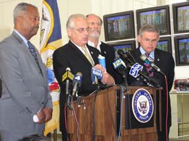 Pascrell is surrounded by Senator Corzine and Congressman Menendez at his left, Congressman Payne is to his right.  All four men stand behind a podium and in front of a six wall mounted monitors and New Jersey's yellow state flag