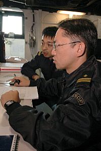 photo - Japanese Maritime Self-Defense Force (JMSDF) officers Lt. Cmdr. Kimihiro Ichiyanagi and Lt. j.g Mitsuhiro Matsumoto discuss shipboard operations on the flag bridge aboard USS Kitty Hawk (CV 63) during the U.S. and JMSDF exercise ANNUALEX.