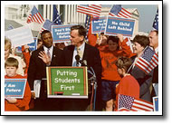 Photo of Senator Gregg speaking to a croud of people, outside of the Capitol, about No Child Left Behind.
