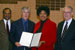 Congresswoman Watson presents a congressional resolution to USC football coach Pete Carroll in recognition of USCs national champion football season (2004).  From left to right: Mike Garrett, USC Athletic Director; Coach Pete Carroll, USC football; Congresswoman Watson; and Dr. Steven Sample, President, USC. The resolution also acknowledges USCs national womens volleyball and mens water polo national championship seasons.