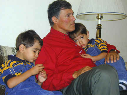 Inslee sits on couch holding two children