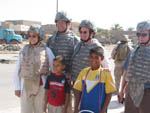 Mary and other Members are greeted by Iraqi children in Baghdad.