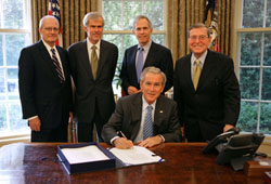 President Bush signs H.R. 2272, with lawmakers nearby.