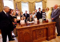 Coleman looks on as President Bush signs into law the Childhood Cancer Act