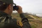 CBP agent watches people as they gather next to the Mexican/American border in Imperial Valley CA.