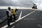 U.S. Navy Senior Chief Petty Officer Ken Crowther holds Seaman Jennifer Boulin as she directs a U.S. Air Force HH 60-G Pave Hawk helicopter as it lands aboard the amphibious dock landing ship USS Tortuga, in the Pacific Ocean, Dec. 1, 2010. U.S. Navy photo by Petty Officer 1st Class Richard Doolin