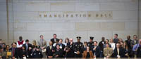 group of people standing in front of wall with bronze letters on it identifying it as Emancipation Hall