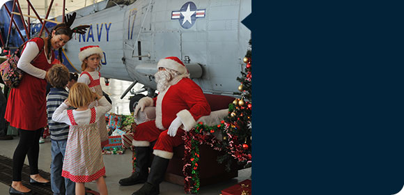 Family visiting Santa Clause in front of Navy aircraft.