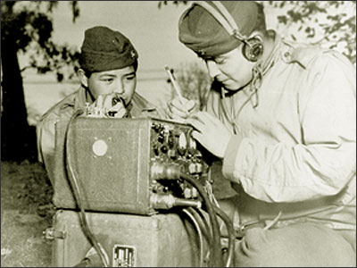 Private First Class Preston Toledo (left) and Private First Class Frank Toledo, cousins and Navajos, attached to a Marine Artillery Regiment in the South Pacific will relay orders over a field radio in their native tongue.