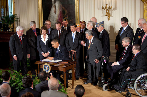 Speaker Nancy Pelosi watches as President Obama signs the bill into law