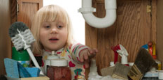 Little girl sneaking into cabinet of cleaning products that could poison her