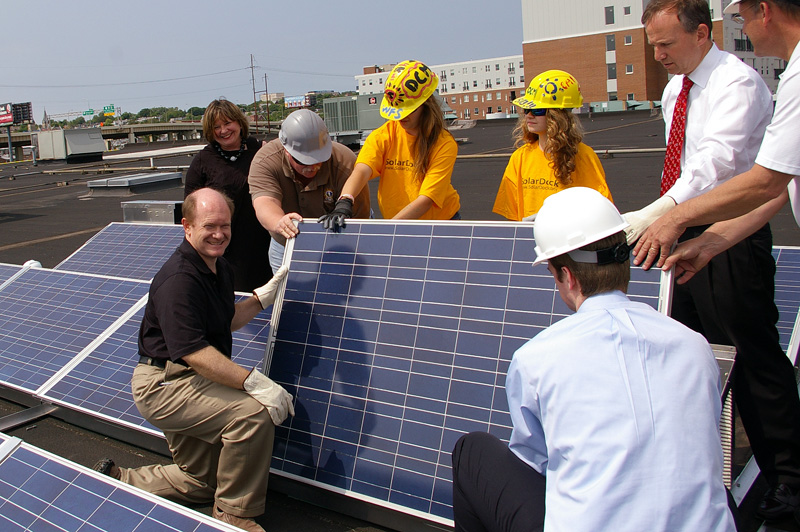 Chris helps install a solar panel on the roof of the Delaware Children's Museum