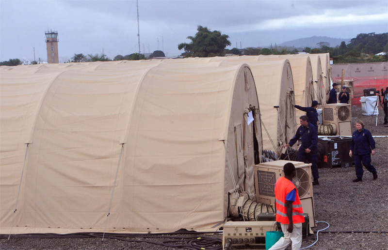 In this photo taken Wednesday Nov. 5, 2014, on the outskirts of the city of Monrovia, Liberia, health workers walk around medical tents that form part of a new American clinic to be used for the treatment of people suffering from the Ebola virus. As the Ebola epidemic flares in new hot spots and dims in others, the response to its shifts must catch up, experts say, and that’s a challenge because it is a slow process for governments to authorize aid, to gather it together and then deliver it. And to build treatment units, even rudimentary ones, takes even more time. By the time it’s built, the outbreak may have moved elsewhere. (AP Photo/Abbas Dulleh)