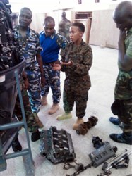 Petty Officer 2nd Class Angel Leonard shows service members with the Nigerian Navy various outboard motor parts during a training engagement in Nigeria, Dec. 2, 2014. Leonard, a Coast Guardsmen with SPMAGTF Crisis Response-Africa is working alongside service members of the Nigerian Navy for a training engagement that began in December. This training engagement will cover basic maintenance, electrical and mechanical skills, and general troubleshooting for small boat engines; the service members will share knowledge of these topics to build operational capacity between the two forces. (Photo by Courtesy Photo)