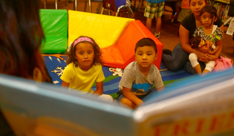 Children and parents listen to a story during story time at a library.