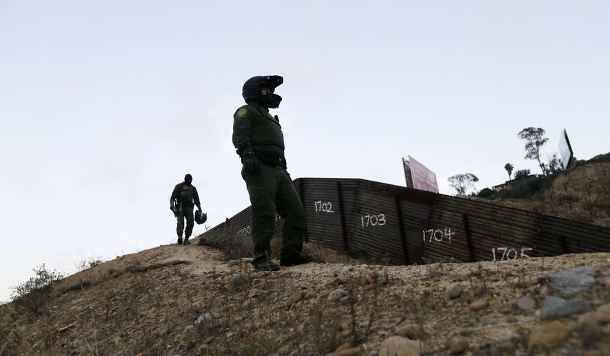 Border Patrol agents look over the primary fence separating Tijuana, Mexico, and San Diego on June 22, 2016. (Associated Press) **FILE**