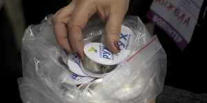 A volunteer distributes buttons for the Cleaning Up Ukraine movement at am anti-corruption forum where Mikheil Saakashvili delivered a speech, in Kharkiv, Ukraine, Jan. 18, 2016. Saakashvili – the former president of Georgia and one of the post-Soviet era’s most contentious and best-known politicians in the region – is making a political comeback in Ukraine as the figurehead of a movement to strip oligarchs of their power. 