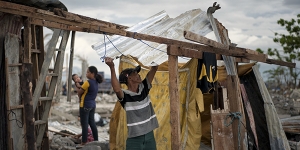 A typhoon victim erects a makeshift house for shelter in Barangay 88, a small coastal village in Tacloban, Philippines, Dec. 7, 2013. Land disputes in settlements and shantytowns up and down the coast are among the many reasons the recovery effort in the area is faltering.