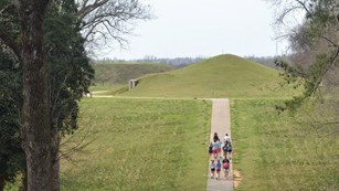 Visitors walking on path to the top of a large prehistoric earthen mound