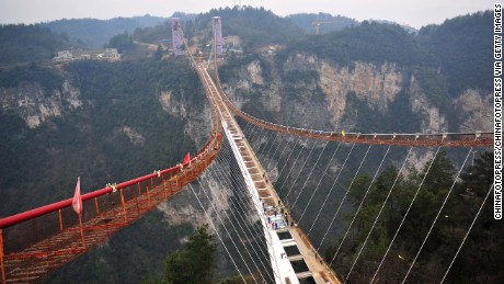 Workers install a piece of glass on a suspension bridge, approximately 300 meters above ground at the Grand Canyon of Zhangjiajie on January 27, 2016. The glass-bottomed bridge, 430 meters in length and 6 meters in width, is expected to open in May this year.