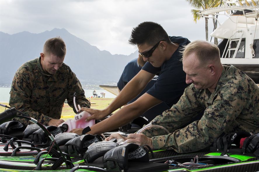 Marines and other personnel make last-minute inspections on self-powered surfboards before a demonstration at Marine Corps Base Hawaii.