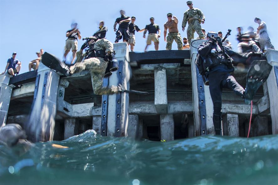 Army Pfc. Aaron Gaugler and Coast Guard Diver 2nd Class Kendall Smith enter the water as part of a pier maintenance training-mission.