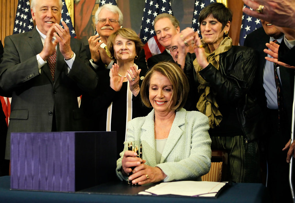 Rep. Slaughter looks on as former Speaker of the House Nancy Pelosi signs the ACA