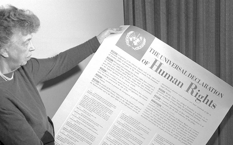 Eleanor Roosevelt holding a copy of the UDHR.