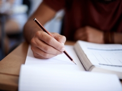 Closeup shot of a young man writing on a note pad