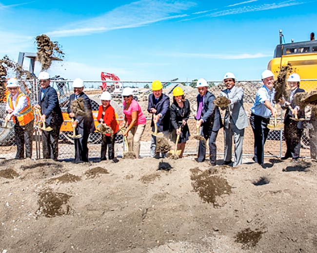 Groundbreaking event with a group of smiling people with shovels in hard hats