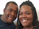 An African American couple smiling at the camera. 