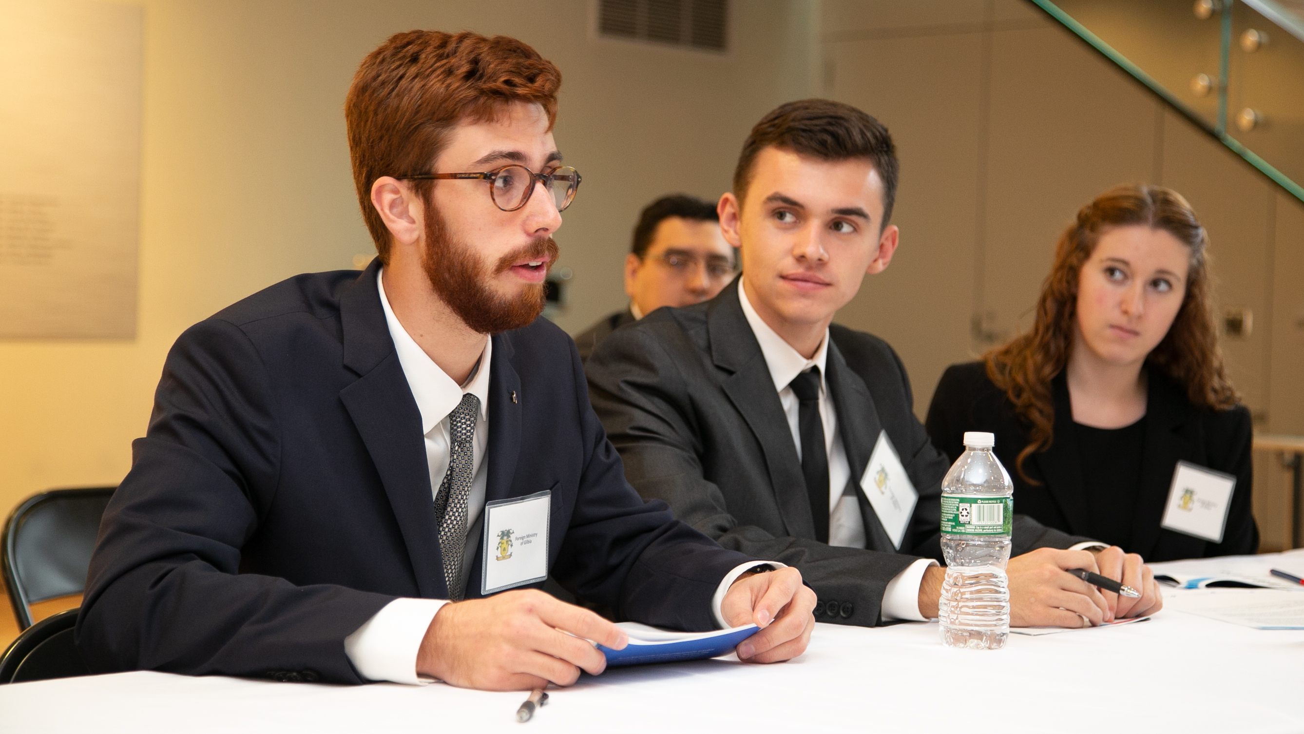 One of three students speak at a table at a simulation.