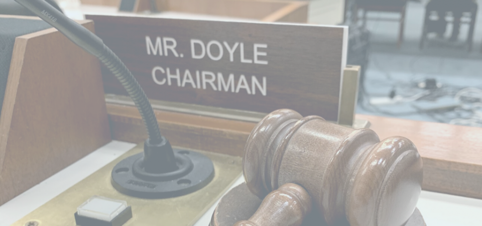 Plaque that reads, "Mr Doyle Chairman" next to a wooden gavel on a podium