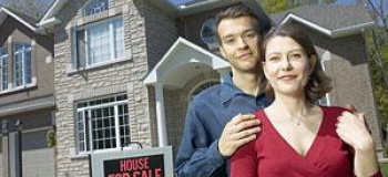 Couple in front of house and for sale sign