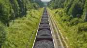 Photo: A train full of coal follows a tree-lined track