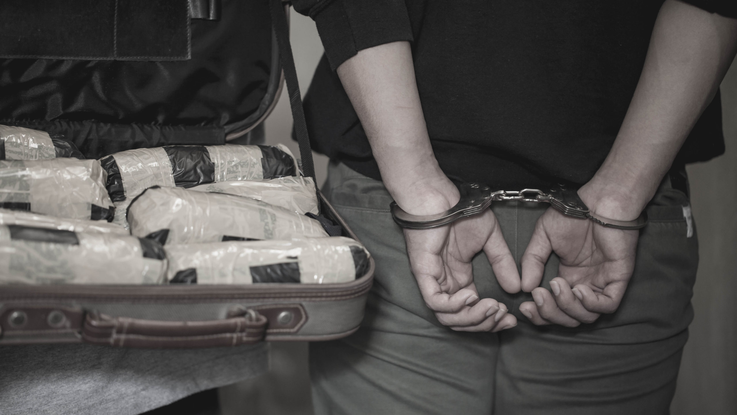 Police arrest drug trafficker with handcuffs. [Shutterstock]