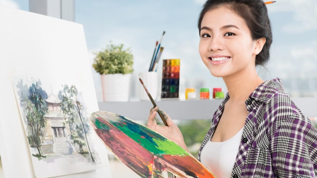 Student artist smiling with paint brush and paint palette