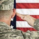 Military soldier saluting an American flag