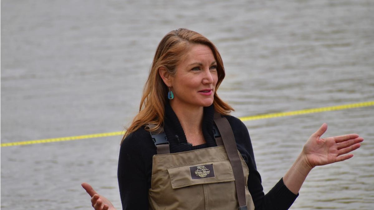 Melanie Stansbury in overalls wading in the Rio Grande.