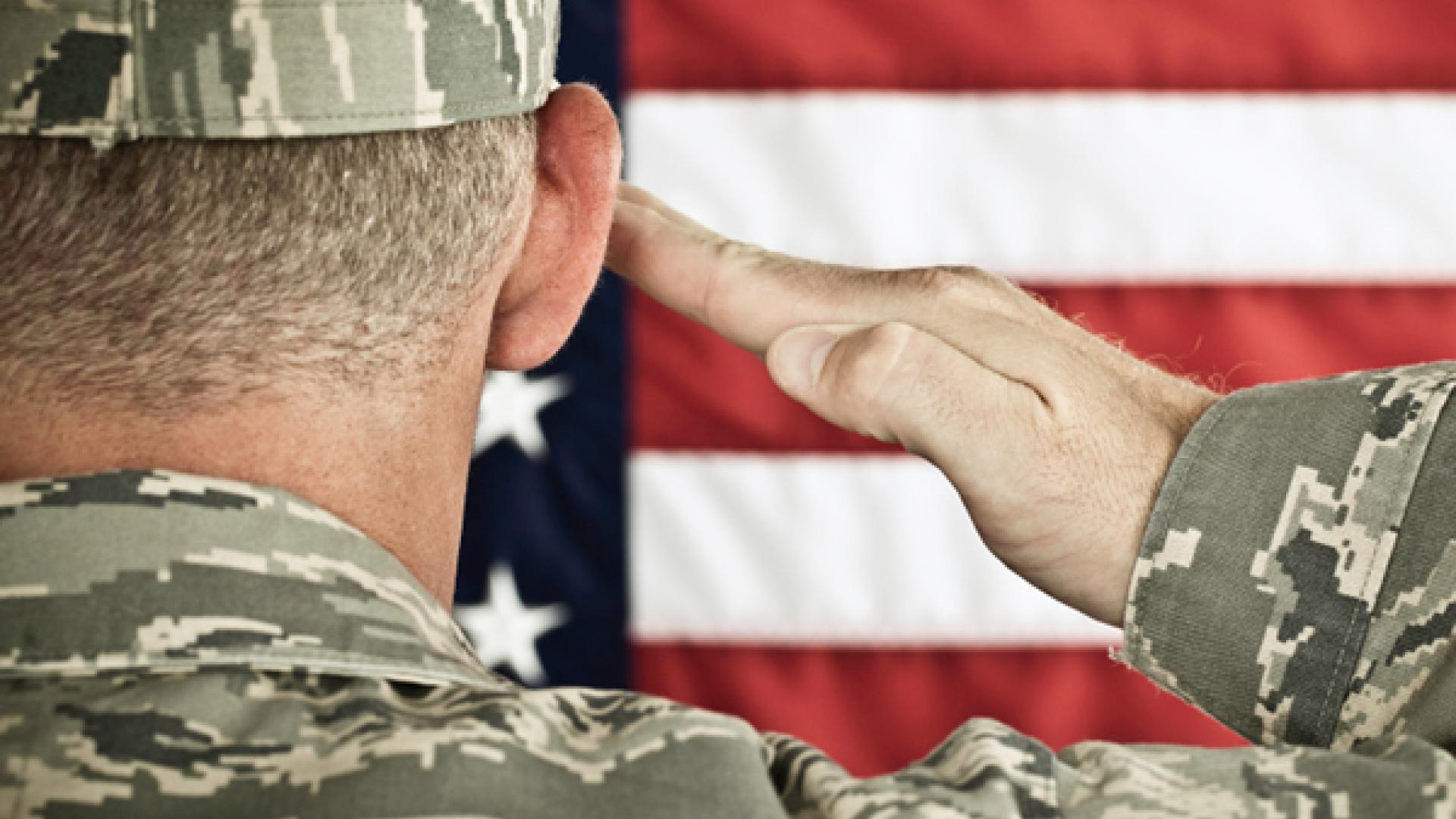 Military soldier saluting an American flag