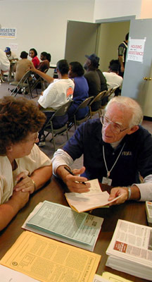 FEMA employee goes over Hazard Mitigation information with a homeowner. Others await their turn to meet with a representative. FEMA photo.