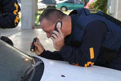 An ICE agent checking the identification number on one a vehicle