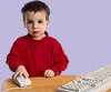 photo of young boy with his hand on a computer mouse beside computer keyboard