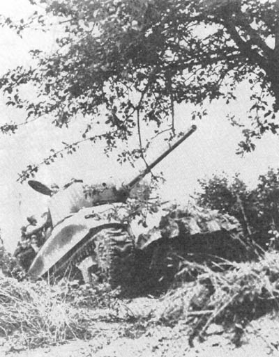 Infantrymen ride on the back of an M-4 Sherman 