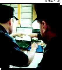 Photograph of two police officers working on a notebook computer