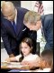 Mariam Karana, a fourth-grade student at Vandenberg Elementary, shows Secretary Paige and President Bush her schoolwork.