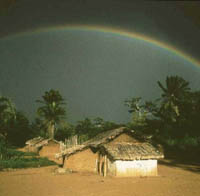 Photo of a house with a rainbow forming in the distance